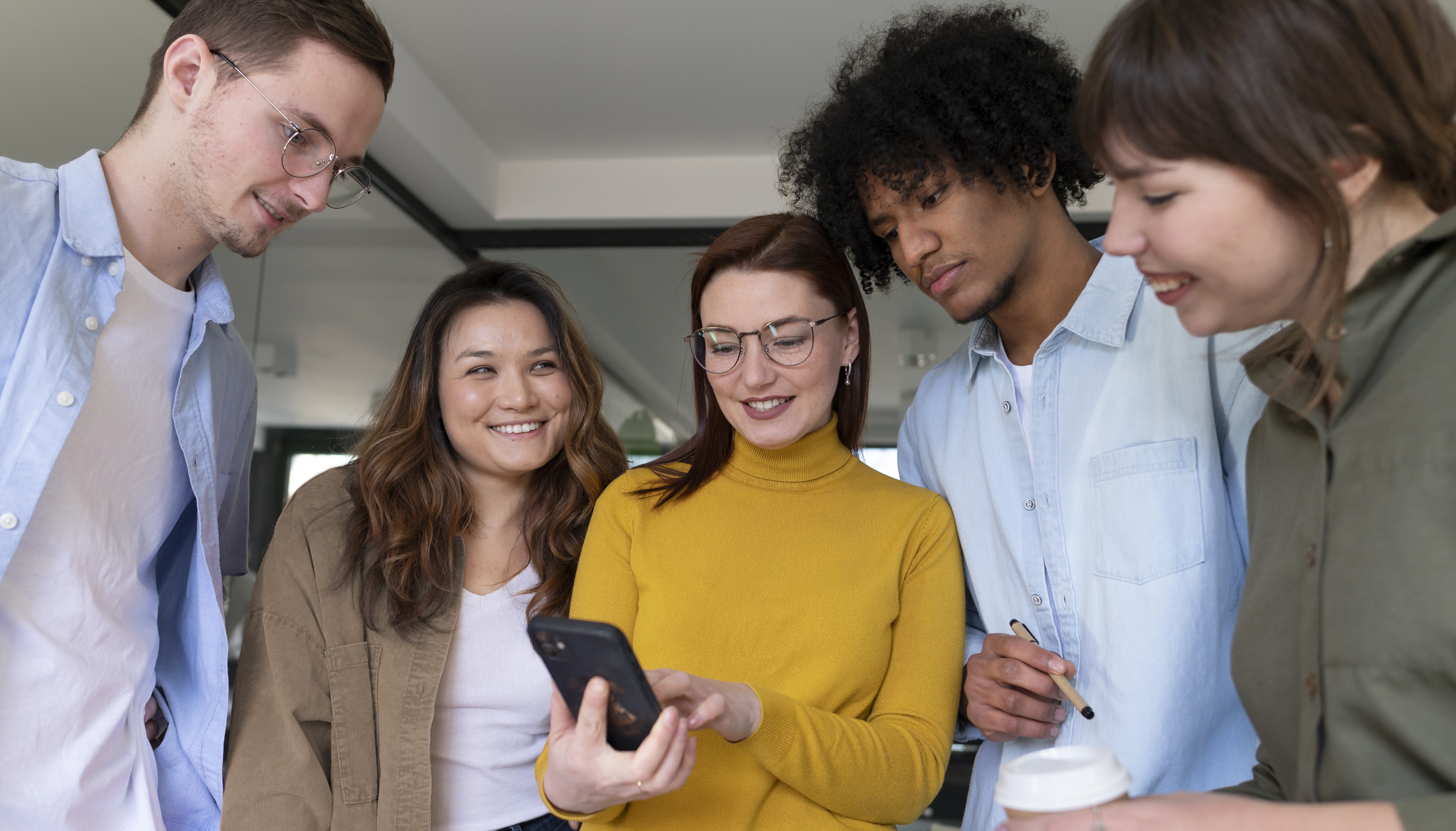Gruppe junger Menschen schaut gemeinsam auf ein Smartphone